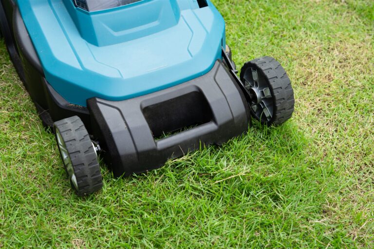 Lawn mower wheels and deck resting on green grass