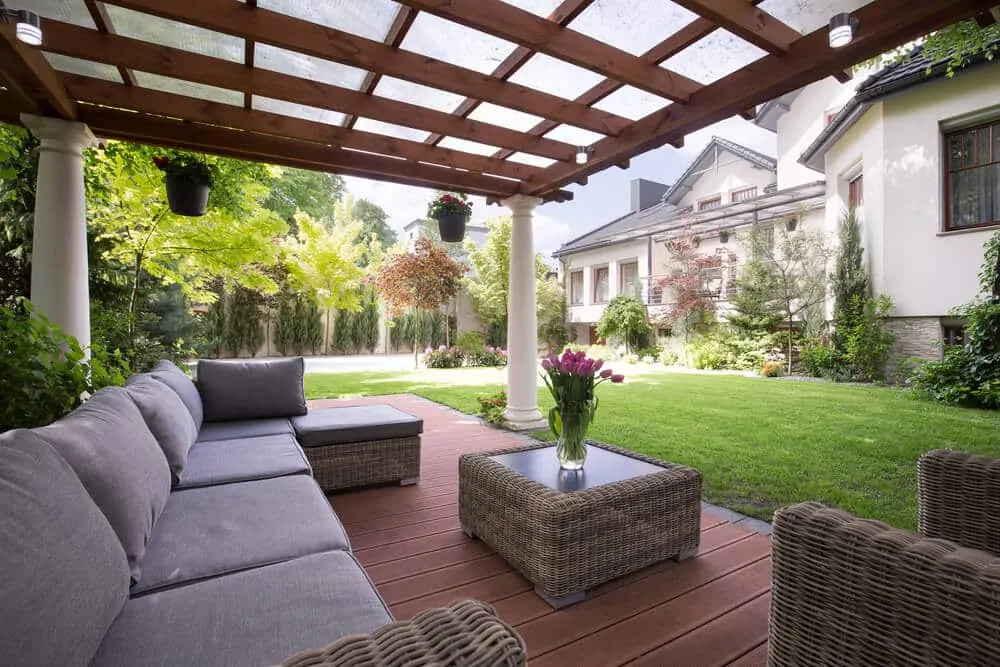 Covered patio with a wooden pergola, outdoor sofa, and a garden view