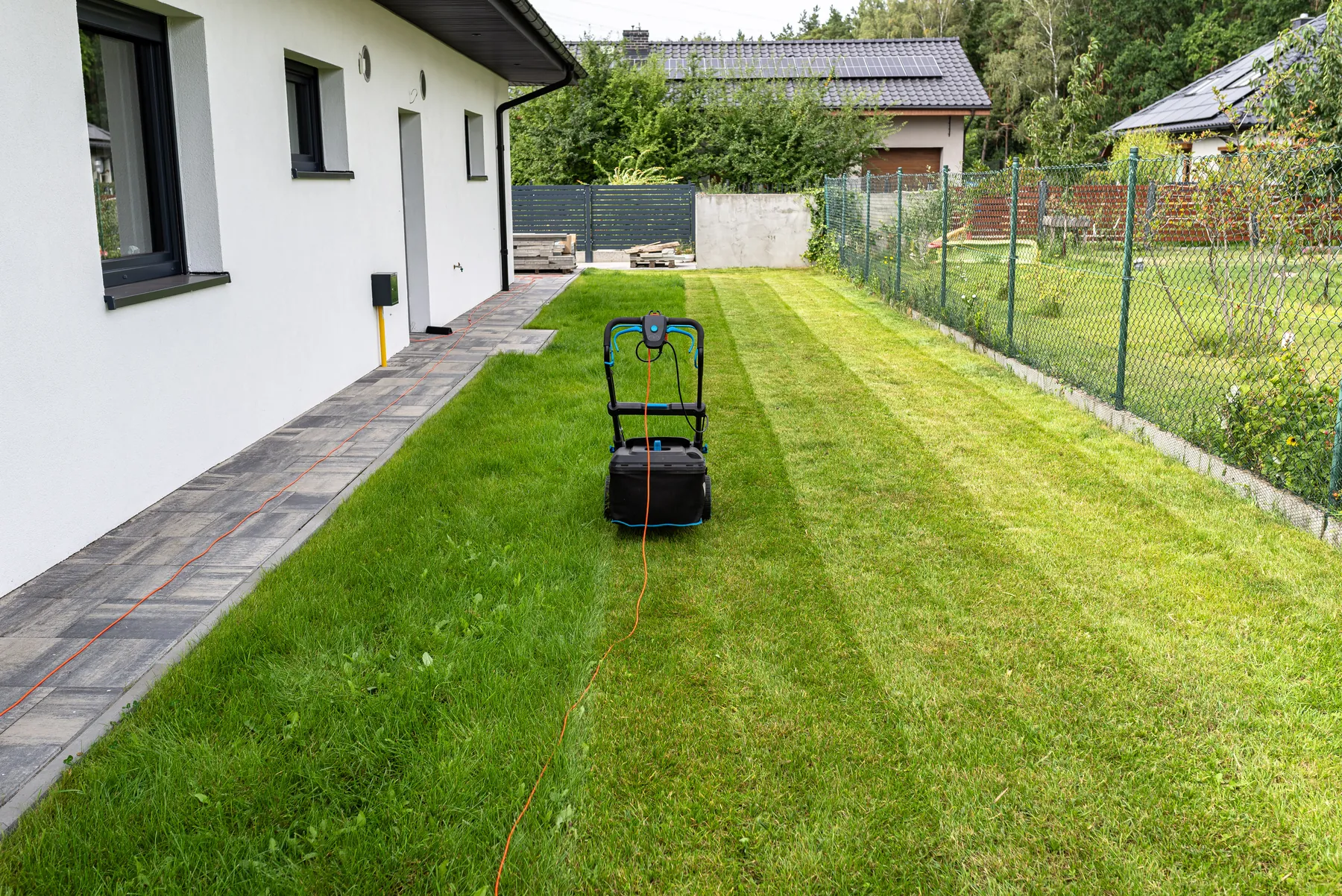 Lawn mower on a freshly striped lawn beside a house