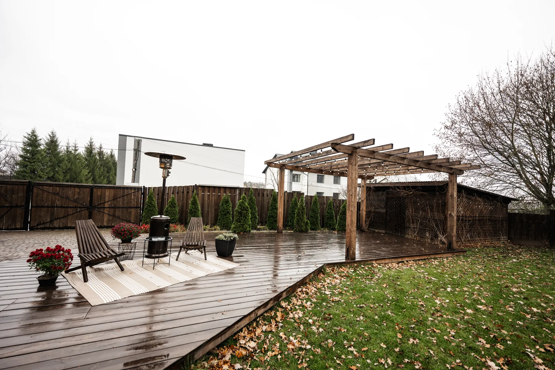 Wooden pergola beside a rain-wet backyard deck on an overcast day