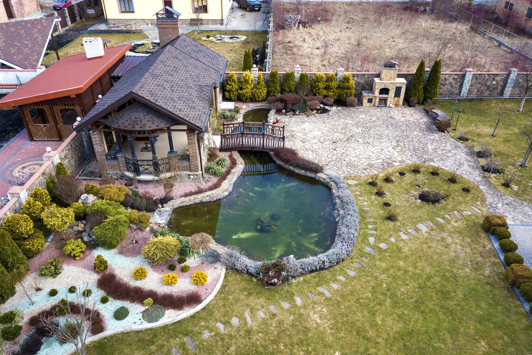 Aerial view of a landscaped backyard with a stone-edged pond, planted beds and a lawn