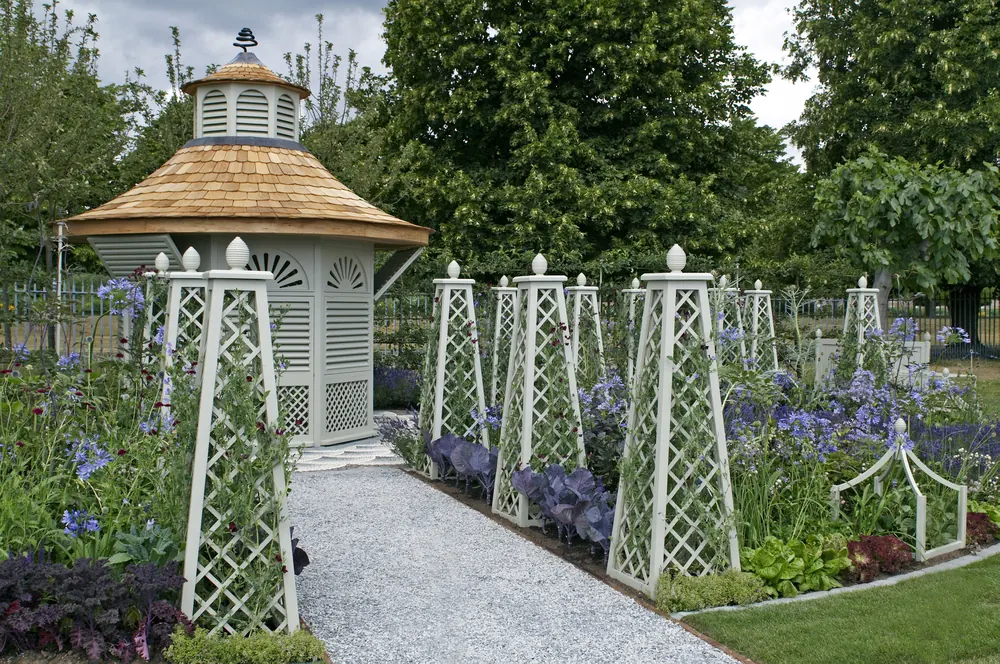 Formal garden with a white gazebo, lattice obelisks, flower beds, and a gravel path